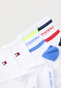 Λευκές κάλτσες αστραγάλου με λογότυπα Tommy Hilfiger, έγχρωμες φτέρνες και ρίγες σε μπλε, κόκκινο και νέον κίτρινο στα μανσέτα.
