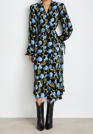 Vestido cruzado negro con estampado floral azul, mangas largas y un lazo en la cintura, combinado con botas de cuero negras hasta la mitad de la pantorrilla.
