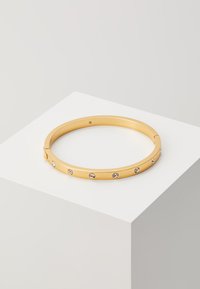 Goldfarbener Armreif mit glatter Oberfläche, der sechs eingelassene Strasssteine hat, die gleichmäßig entlang der äußeren Kante verteilt sind.