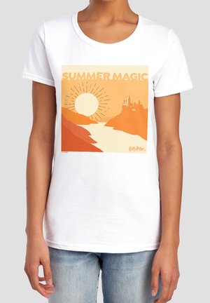 Woman wearing a white t-shirt with an orange "Summer Magic" landscape featuring a river, sun, and castle silhouette, labeled Harry Potter.