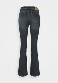 Jean flare bleu foncé vu de dos avec deux poches et une petite étiquette en cuir marron sur la ceinture.