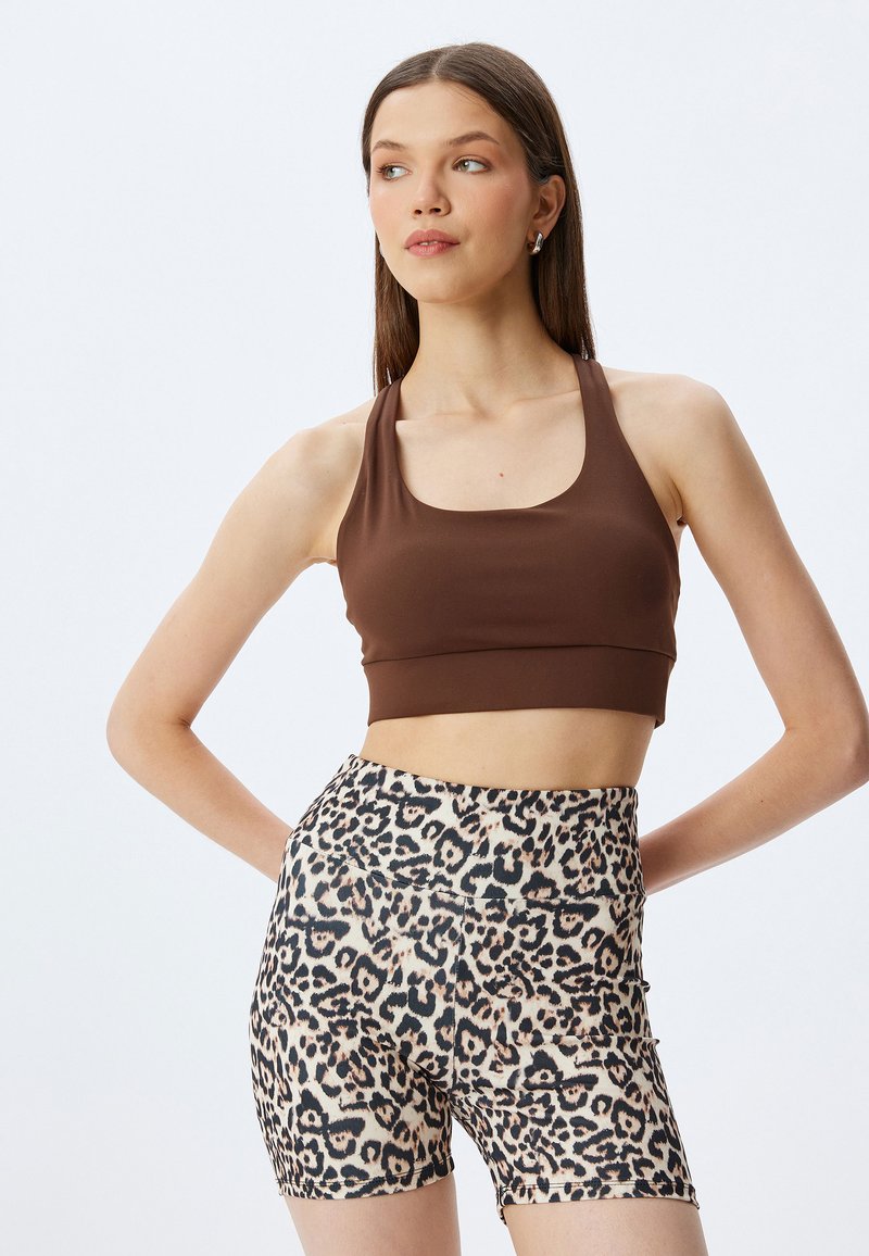 Brun sports-bh med scoop-udskæring parret med højtaljede leopardmønstrede shorts med en tætsiddende design og glat tekstur.