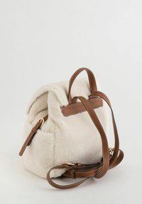 Mochila de forro polar crema con detalles de cuero marrón, que cuenta con una solapa superior, correas ajustables y herrajes de tono dorado.