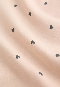 Világos rózsaszín anyag, kis fekete szív alakokkal egyenletesen szórva a felületen, textúrával és enyhe redőkkel.