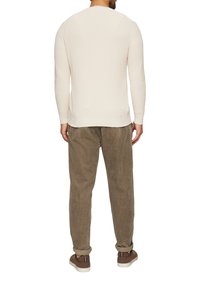 Lichtcrème brei sweater met een gestructureerd patroon, gecombineerd met olijfkleurige corduroy broek en bruine sneakers, gezien vanuit de achterkant.