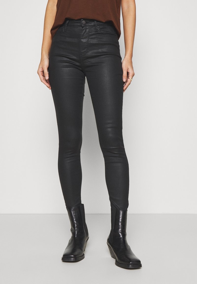 Jean skinny noir en matière lisse et extensible, avec poches avant, fermeture par bouton et fermeture éclair, et design taille haute.
