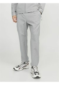 Joggers deportivos grises hechos de una tela suave, con un corte ajustado, bolsillos laterales y detalles en panel. Combinados con zapatillas voluminosas en blanco y negro.