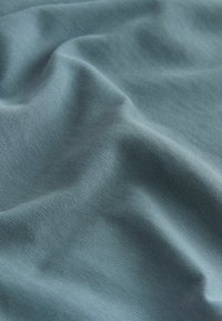 Material de un blue deschis, cu o textură netedă, care prezintă drapaje delicate și un model de țesătură fină. Fără accente notabile sau accesorii.