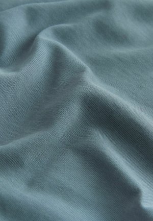 Svetloblúza látka s hladkou textúrou, ktorá ukazuje jemné záhyby a jemnú tkaninovú štruktúru. Žiadne výrazné akcenty ani kovania.