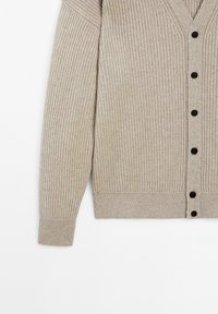 Beige geribbelde gebreide cardigan met lange mouwen en zwarte knopen aan de voorkant, weergegeven op een witte achtergrond.