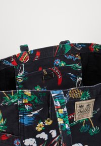 Černá textilní taška s barevným tropickým vzorem; má ucha, vnitřní kapsu a malou značkovou visačku; bavlněný materiál.