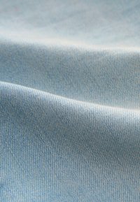 Svijetloplavi traper s glatkom teksturom i blagim sjajem, s prikazom suptilnog keper uzorka i mekom pada.