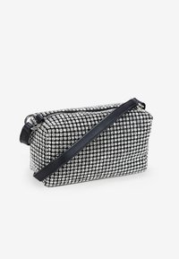 Bolso rectangular negro y plateado con una superficie texturizada cubierta de pequeños strass y una correa de cuero desmontable.