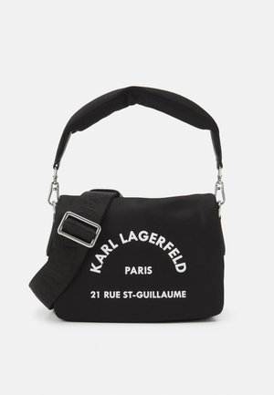 Czarna torebka Karl Lagerfeld z wyściełanym uchwytem, regulowanym paskiem na ramię oraz białym napisem "Karl Lagerfeld Paris 21 Rue St-Guillaume" z przodu.