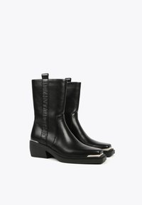 Black leather ankle boots with a square toe, block heel, and logo detail on the side. Features stitching and a shiny metal accent on the toe.