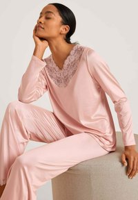 Roze satijnen pyjama set met een V-hals top met kantafwerking en lange mouwen, en bijpassende taps toelopende broek met kantaccenten aan de zoom.