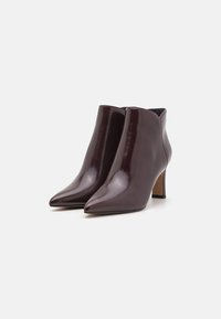 Burgunderfarbene Leder-Stiefeletten mit glänzendem Finish, spitzem Zeh und einem mittelhohen Stiletto-Absatz. Glatte Textur mit minimalistischem Design.