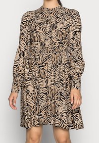 Långärmad klänning i mjukt tyg, med ett mönster av svart och beige tigerstrip, avslappnad passform och hög krage.