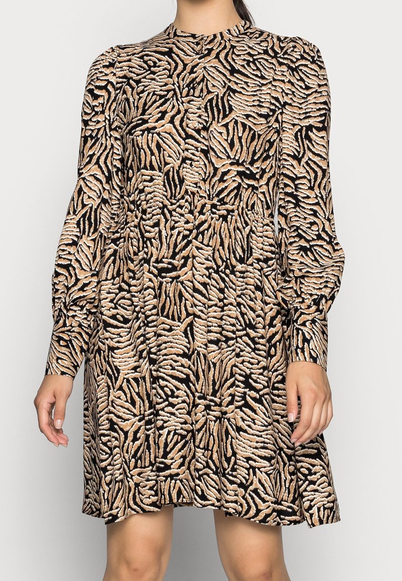 Långärmad klänning i mjukt tyg, med ett mönster av svart och beige tigerstrip, avslappnad passform och hög krage.