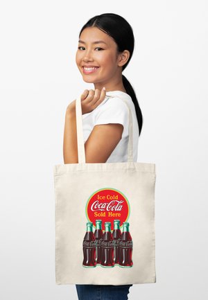 Bawełniana torba na zakupy z vintage'owym wzorem Coca-Coli, przedstawiająca okrągłe czerwone logo oraz ilustracje szklanych butelek. Tło jest zwykłe białe.