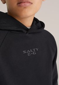 Črna kapuca s puloverjem iz mehkega blaga, s poudarjenim sivim logotipom "SALTY D.G" na prsih in teksturirano kapuco.