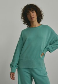 Türkiser, oversized Sweatshirt aus weichem Material mit gerippten Bündchen und Saum. Lockere Passform, mit rundem Halsausschnitt und seitlichen Nahtdetails.