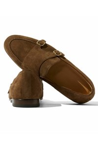 Bruine suède instappers met twee gouden gespen, een ronde neus en een lage houten hak. Bevat een gladde binnenvoering.