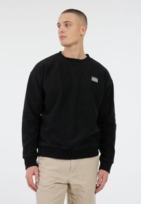 Zwarte fleece sweatshirt met een ronde halslijn en geribbelde manchetten, voorzien van een klein blauw-wit logo-opdruk op de borst.
