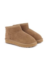 Botas de tobillo de ante marrón con punta redonda, suela de goma plana y costuras mínimas. Diseño simple con una textura suave. Sin detalles metálicos.