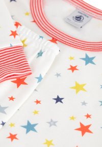 Σετ λευκή πυτζάμα με πολύχρωμα αστέρια σε κόκκινο, πορτοκαλί, κίτρινο, μπλε και γκρι. Μανσέτες και λαιμόκοψη με κόκκινες ρίγες. Απαλό βαμβακερό ύφασμα.