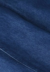 Donkerblauwe denimstof met een twill-weefsel, met een gladde structuur en subtiele spikkels. Zichtbare stiksels langs de randen.
