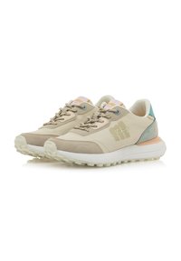 Zapatillas deportivas beige con superposiciones texturizadas, cierre con cordones, acento azul claro en el talón y suela blanca resistente.