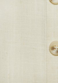 Helle Leinwand mit einer subtilen Textur, ausgestattet mit einem transparenten Knopf auf der linken Seite, der ein glattes, ungeschmücktes Design zeigt.