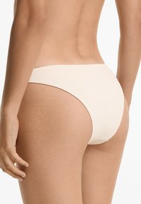 Chiloți de baie bej deschis, dintr-un material texturat, cu o acoperire medie și un design simplu. Margini fără cusături și stil minimalist.