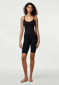 Czarna koszulka na ramiączkach i zestaw szortów rowerowych, wykonany z miękkiej elastycznej tkaniny, oferujący dopasowany krój i regulowane ramiączka dla większego komfortu.