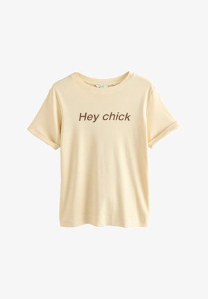 Kortærmet, lysegul t-shirt med rullemanchetter, prydet med teksten "Hey chick" i mørkebrun centreret på forsiden. Blødt bomuldsstof.