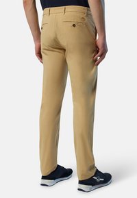 Pantaloni beige realizzati in tessuto leggero, dotati di due tasche posteriori con chiusura a bottone e design con gamba dritta.