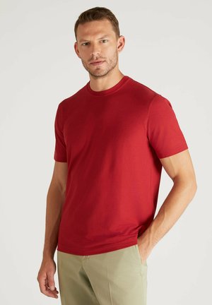 Rode katoenen T-shirt met korte mouwen, ronde hals en een gladde textuur. Gecombineerd met lichtgekleurde broek.