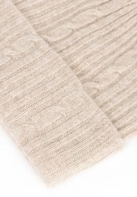 Beżowy dziergany szalik o fakturowanym wzorze prążków i warkocza, wykonany z miękkiego materiału, prezentujący złożony fragment.