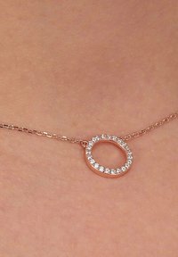 Collana in oro rosa con un pendente circolare decorato con gemme trasparenti lungo il bordo esterno, montato su una delicata catena.