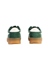 Baskets en daim vert avec un accent blanc, présentant une finition texturée et une semelle en caoutchouc gomme. La marque "Gola" est visible sur le talon.