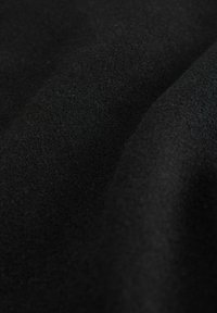 Melnā auduma ar mīkstu, teksturētu apdari, kurai ir matēta virsma un smalkas toņu variācijas, radot gludu, plūstošu izskatu.