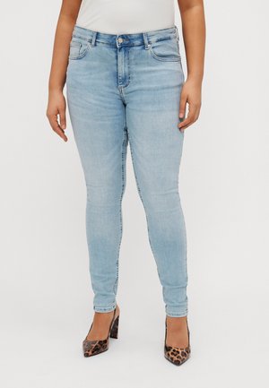 Light blue skinny jeans with a high waist, featuring front pockets and subtle fading. Worn with leopard-print heels. Smooth denim texture.