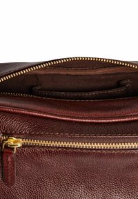 Bruine leren tas met een gestructureerd oppervlak. Voorzien van een gouden ritssluiting en een donkere voering met een intern vak.