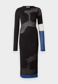Svart stickad klänning med långa ärmar, med nätmönster, en blå ärm och beskärning längst ner. Designen inkluderar olika texturer.