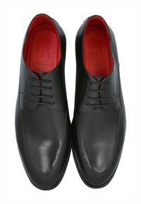 Zapatos de cuero negro con acabado liso, forma redondeada y cinco ojales. Interior con forro rojo intenso. Marca sutilmente visible.