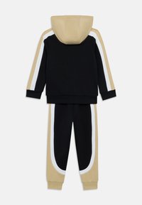 Σετ με μπλούζα με κουκούλα και παντελόνι φόρμας σε μαύρο, ταμπά και λευκό. Διαθέτει σχεδιασμό με μπλοκ χρωμάτων, αντίθετες λωρίδες στα πλαϊνά και άνετη εφαρμογή.
