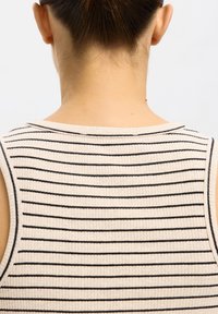 Rückenansicht einer Person mit braunem, zusammengebundenem Haar, die ein ärmelloses beiges Oberteil mit dünnen schwarzen horizontalen Streifen trägt.
