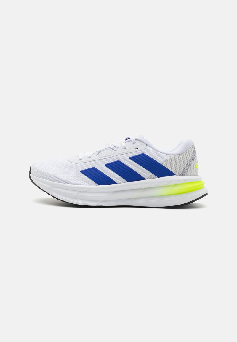 White athletic shoe with blue accents and three stripes on the side, featuring a textured fabric upper and a neon green sole.