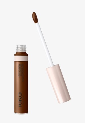 Kiko Milano Love Fusion 24-timers fuktighetsgivende strålende concealer med en applikator med myk svamp, nyansen medium brun, mot en hvit bakgrunn.